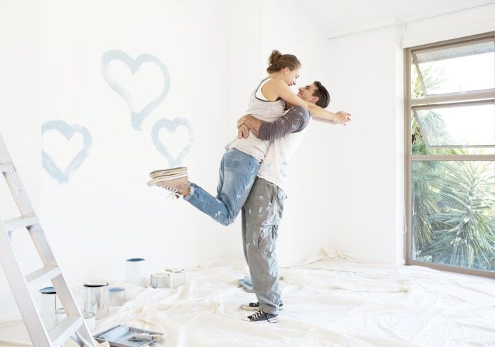 Couple painting blue hearts on wall