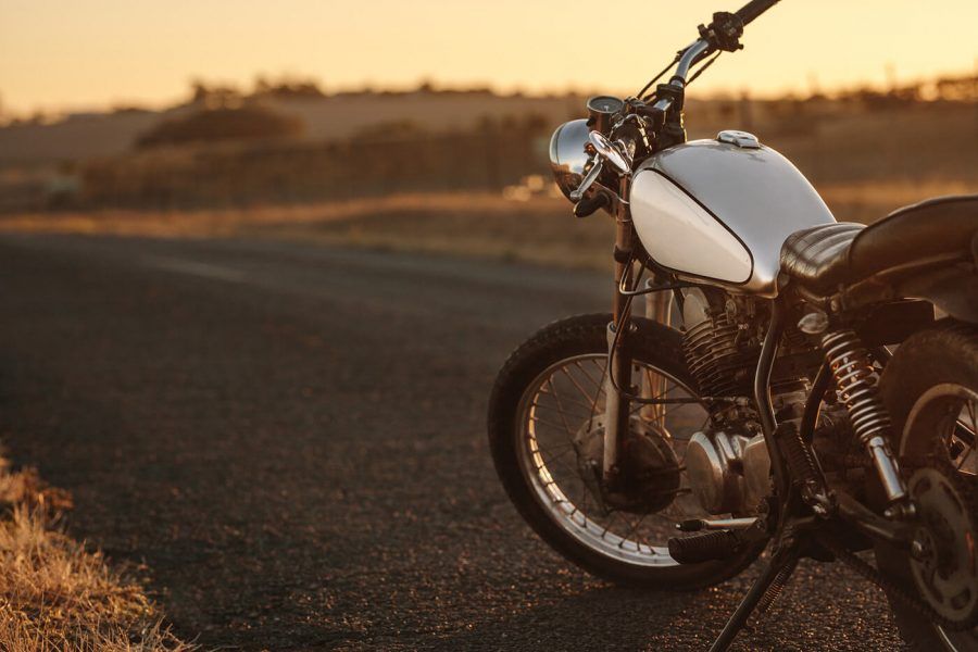 Vintage motorcycle parked on empty country road. Vintage motorbike standing at the side of the road in evening.