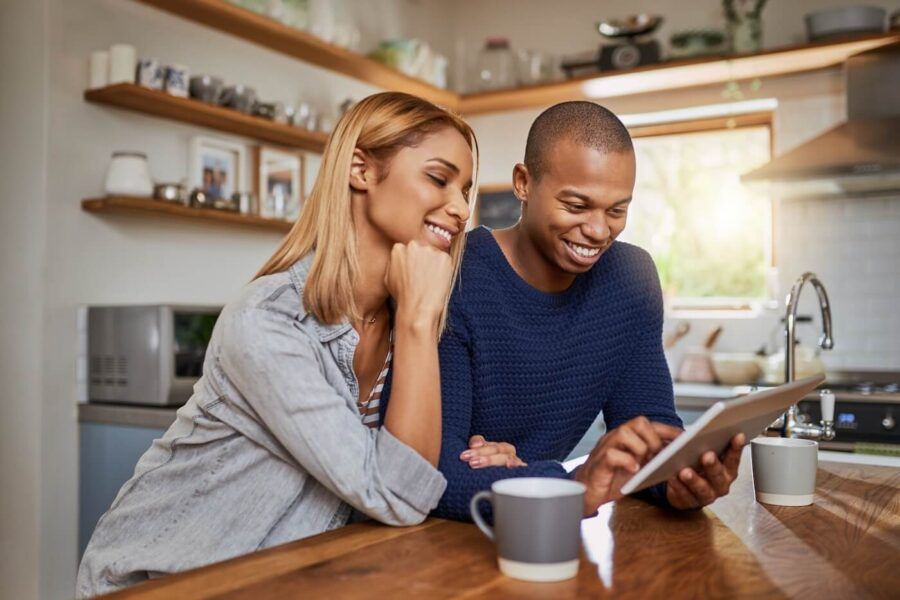 Couple checking their credit score on a tablet while having coffee