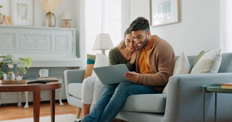 A man and a woman sitting together on their couch, using a laptop.