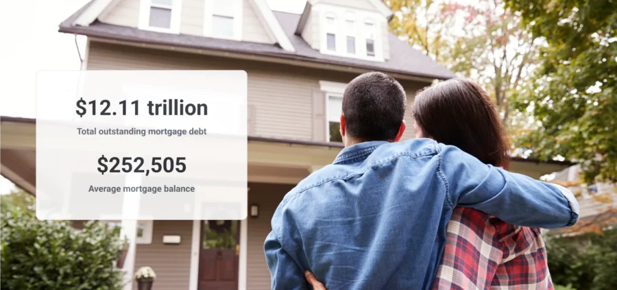 A happy couple looking up at their new house. There is black text superimposed on a white background that reads $12.11 trillion total outstanding mortgage debt and $252,505 average mortgage balance.