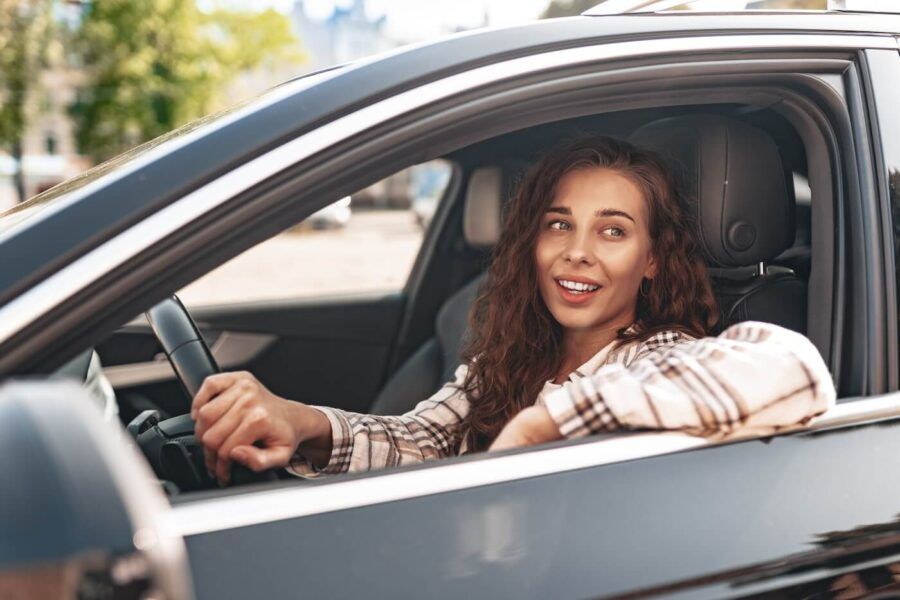 Smiling young woman driving a car
