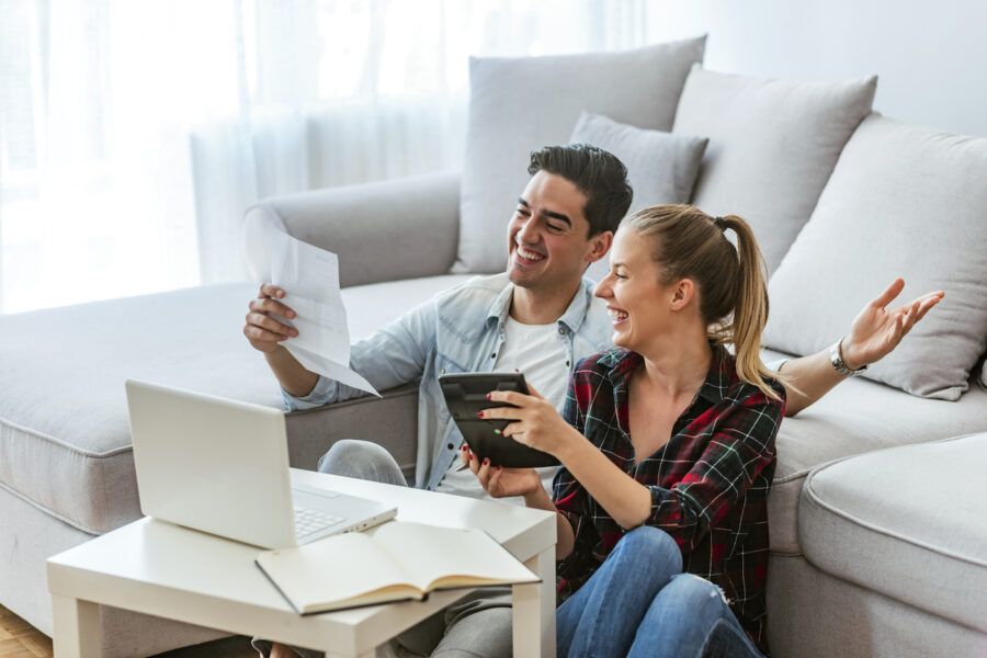 Photo of a happy couple doing finances at home, managing their savings account effectively.