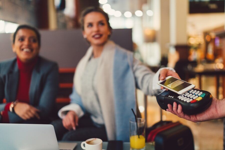 Young women making a contactless payment using a digital wallet in a restaurant.