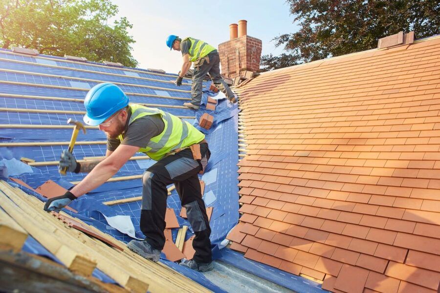 Two male workers fixing the house roof on a sunny day