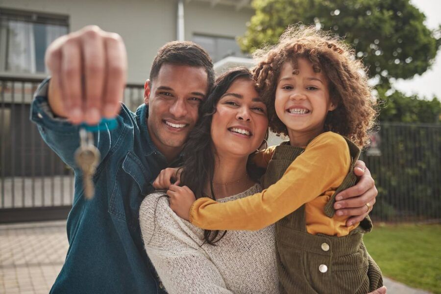 A happy family of three holding the key from their new home