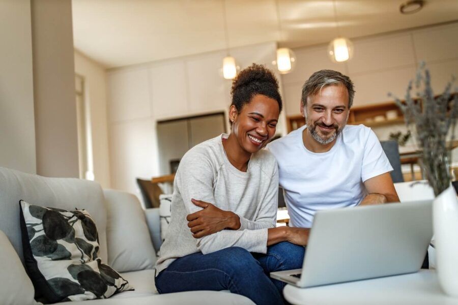 Happy couple using laptop at home