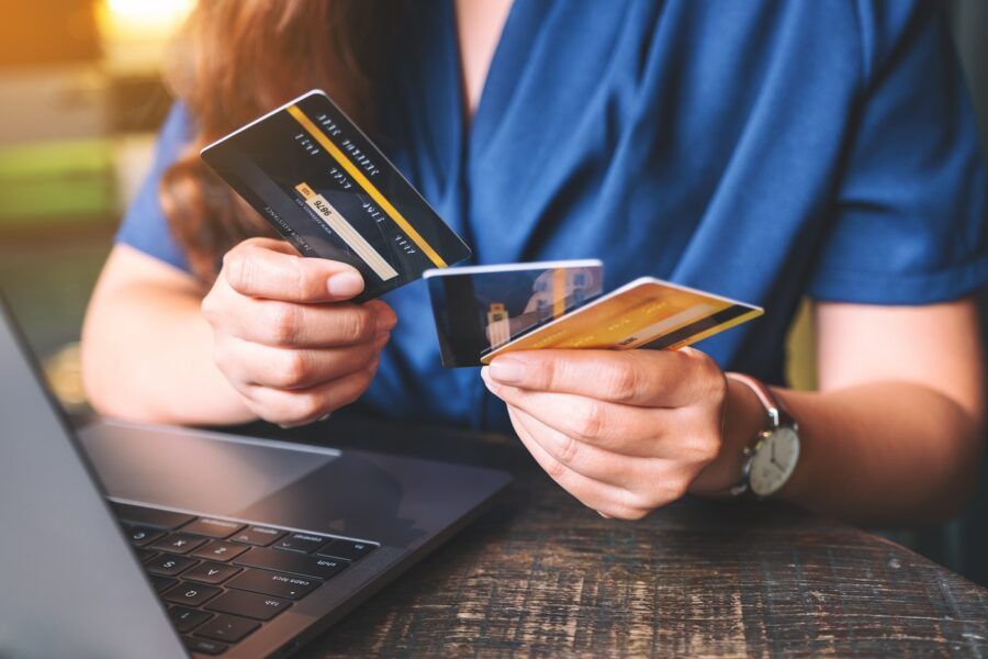 Closeup image of a woman holding and choosing credit cards while using laptop computer.