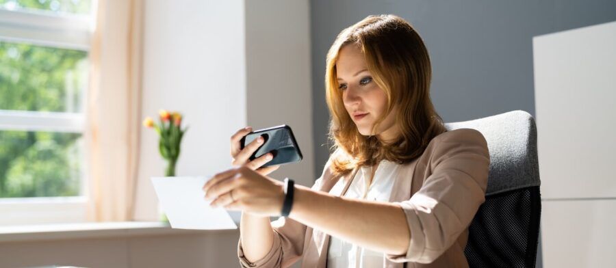 Young business woman deposits a check via mobile banking app