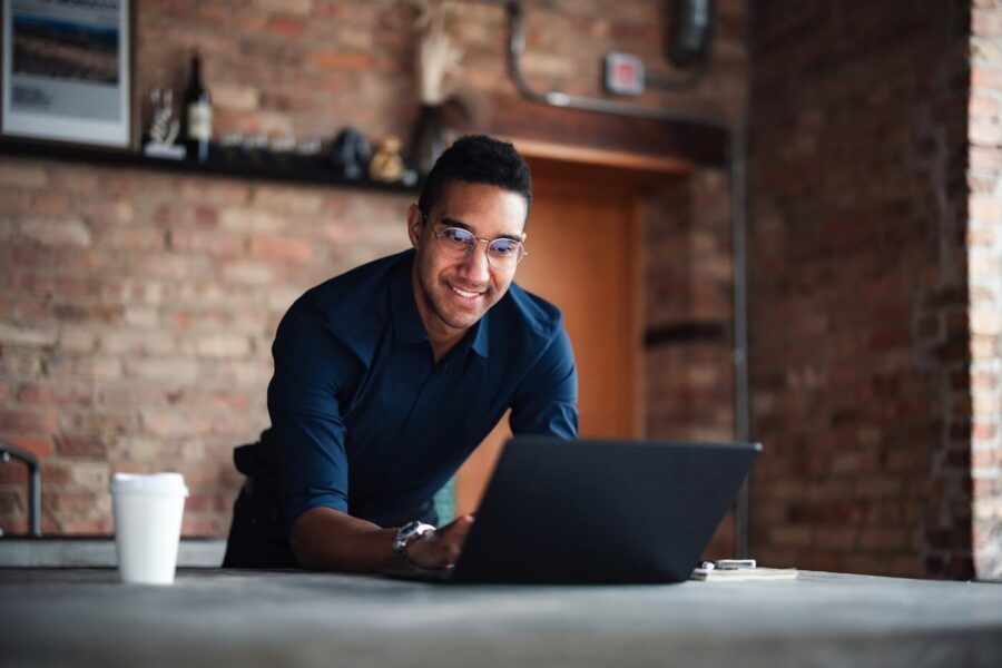 Smiling man wearing glasses using his laptop in the modern living room