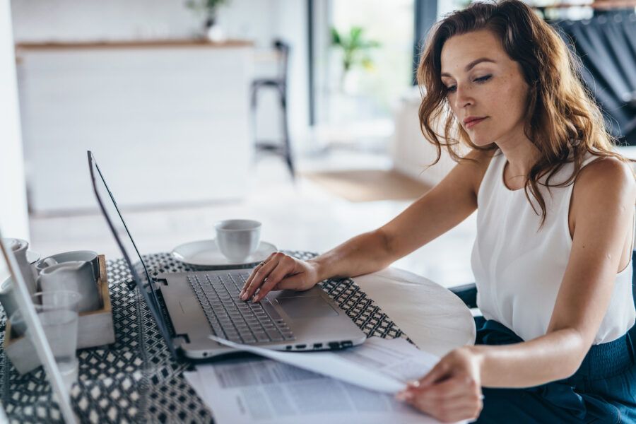 Woman using laptop while sitting at table.