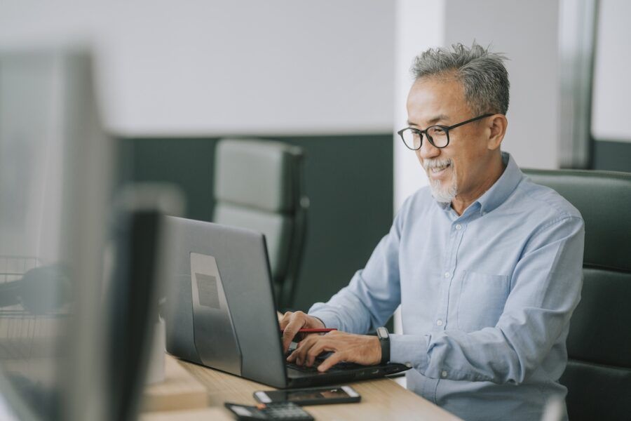 A senior man with facial hair using laptop to check his credit score.