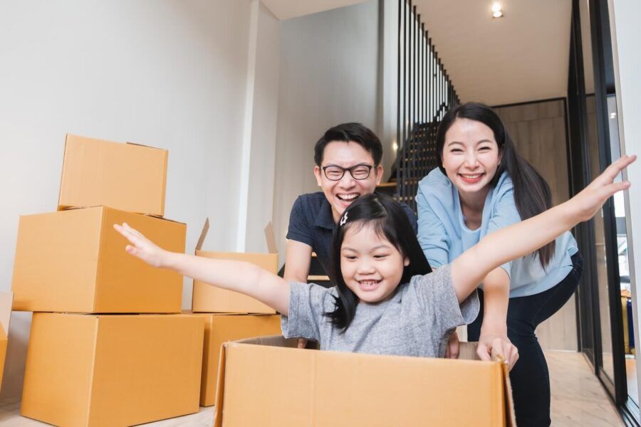 Happy family with a young girl playing with the moving boxes in their new house