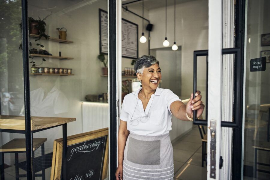 Small business owner standing in a coffee shop front door.