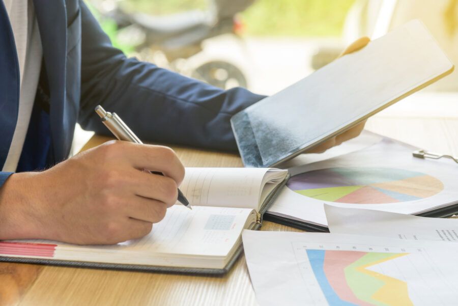 Man writing in notebook analyzing his debt-to-credit ratio