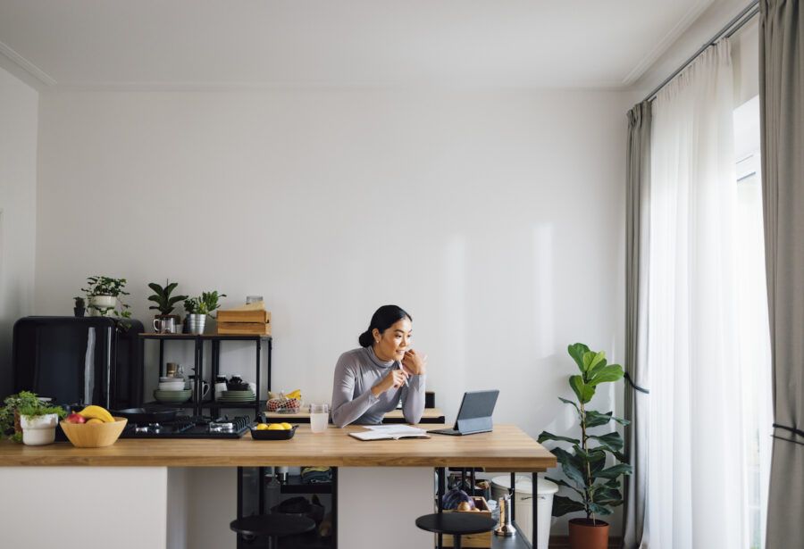 A woman using digital tablet at kitchen desk.