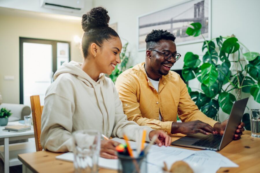 Newlywed couple using laptop while sitting at the table together at home.