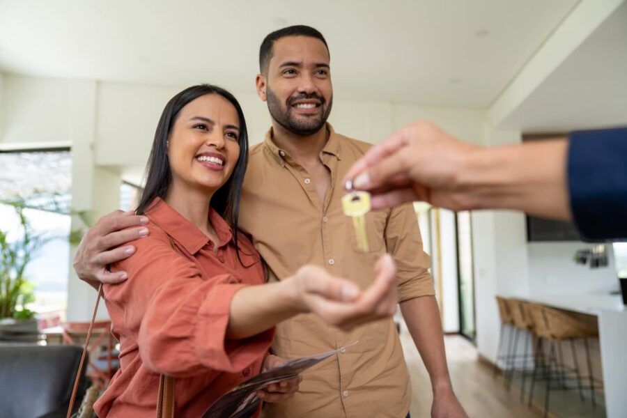 Happy couple taking the new house keys from the real estate agent