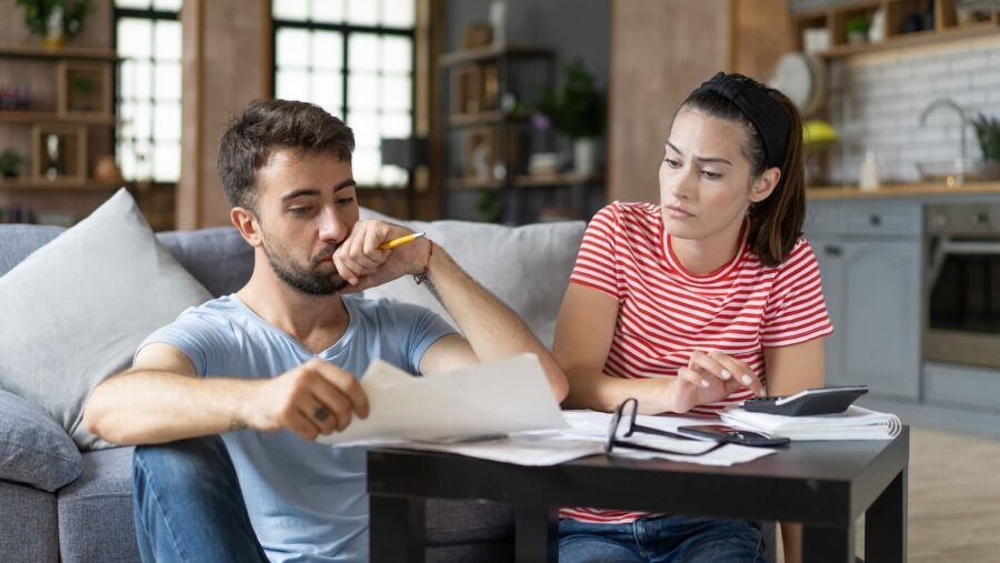 Frustrated young couple reviewing their bills at home