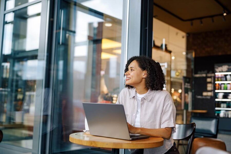 Smiling woman working on a laptop at an outdoor café