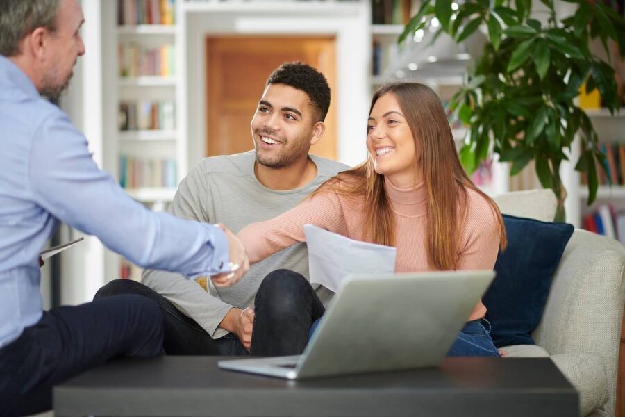 Happy young couple shaking hands with a male mortgage broker