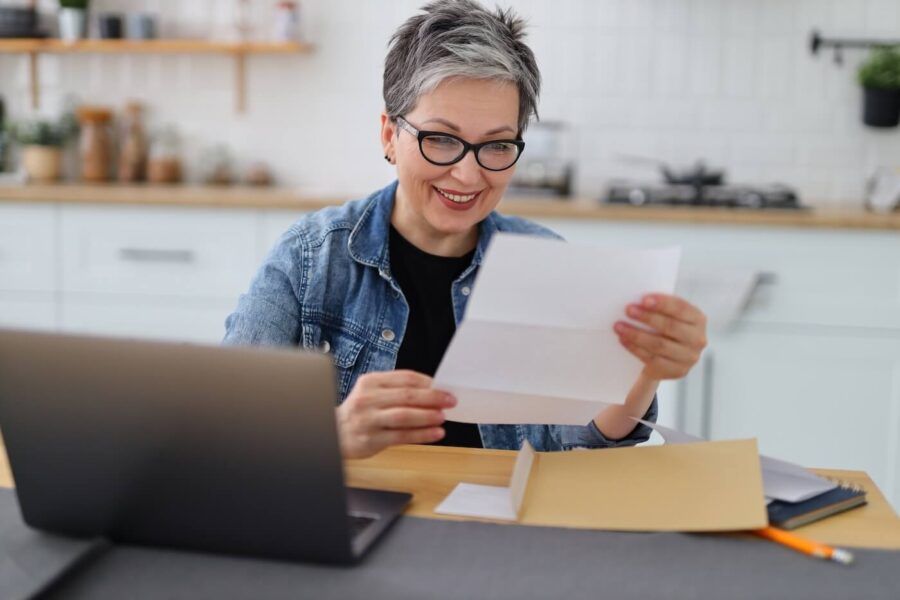 Mature woman reading her mail while using her laptop at home