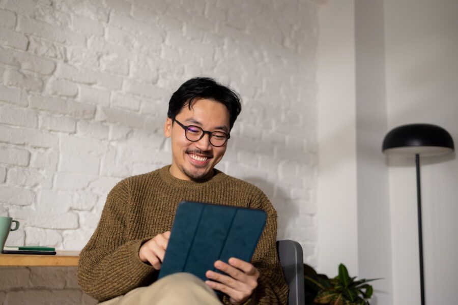 Young man sitting at his home office while looking at CD loan options using tablet