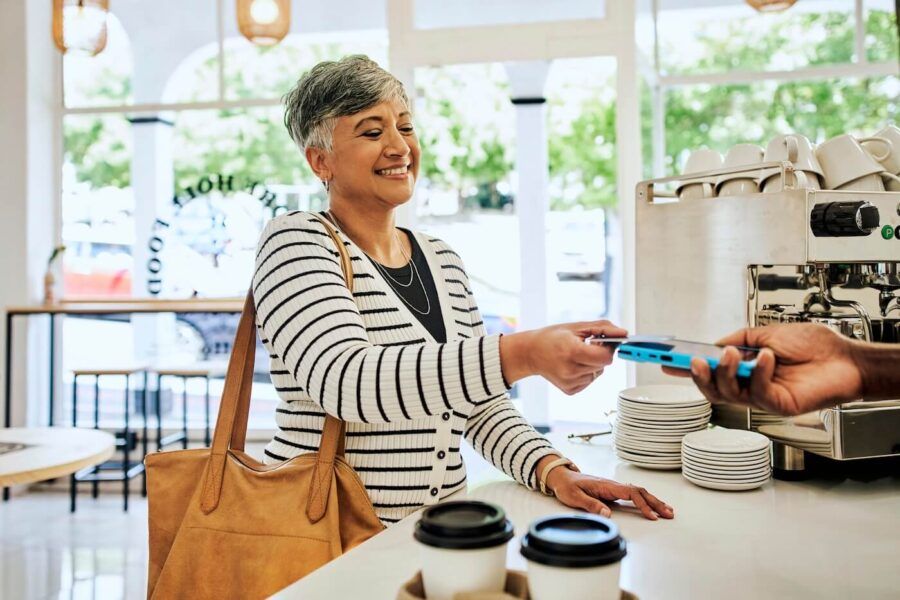 Smiling mature woman paying with her credit card in a cafe