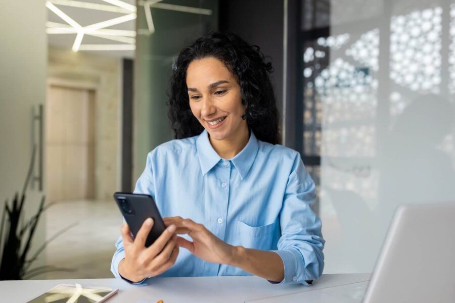 Smiling woman checking her smartphone in the office
