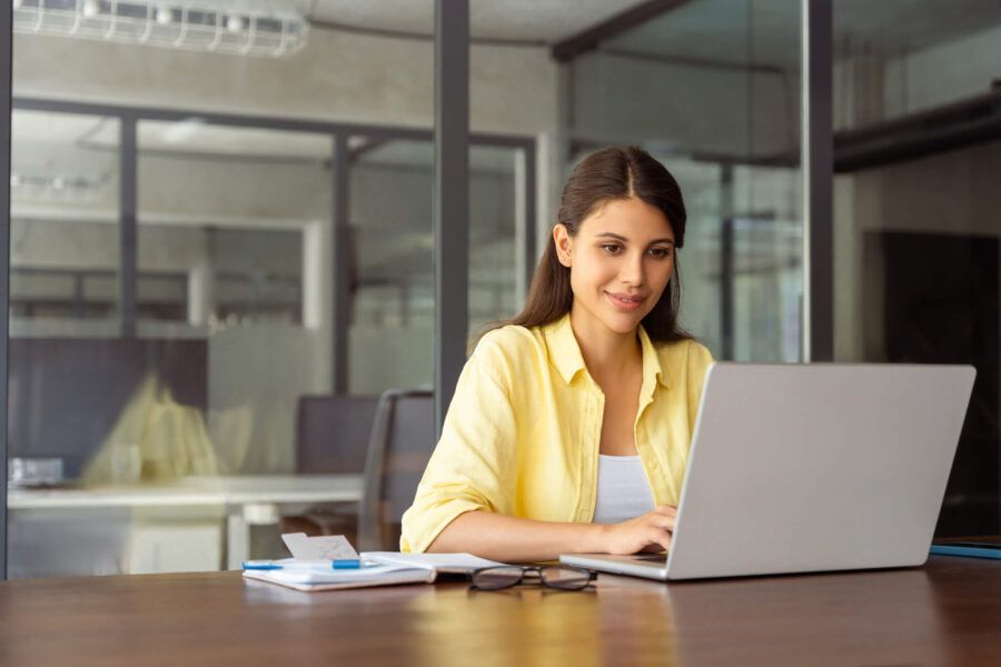 Smiling businesswoman using her laptop in the office