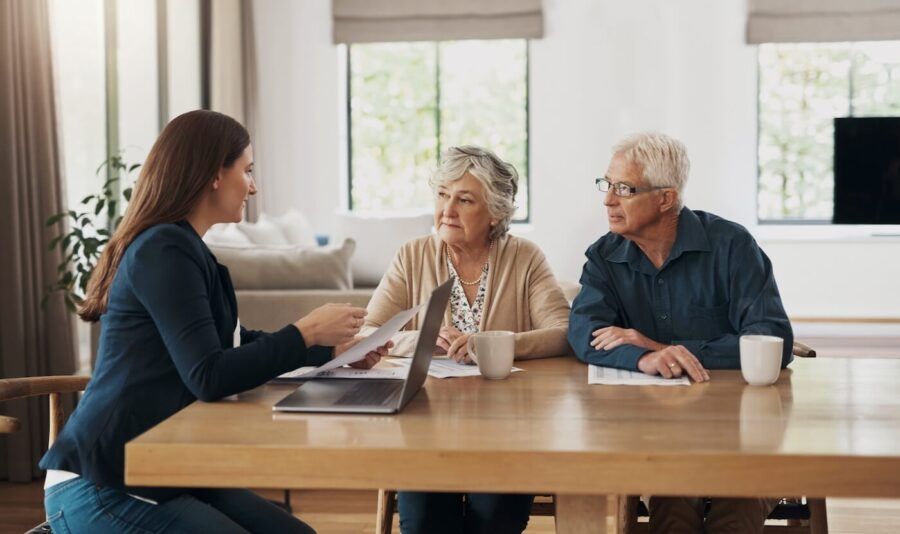 Senior couple having a meeting with a female investing broker at home