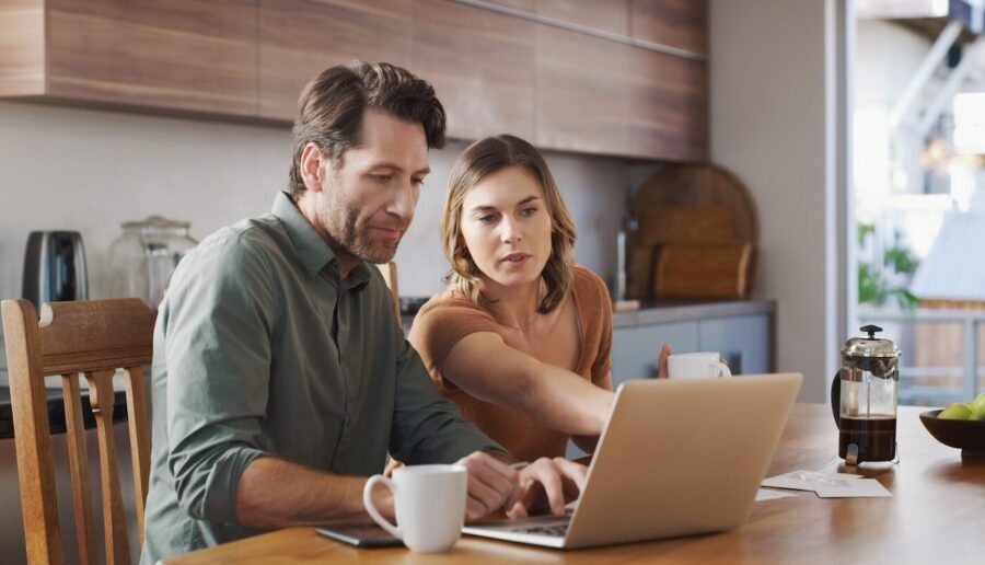 Focused couple using a laptop in the kitchen