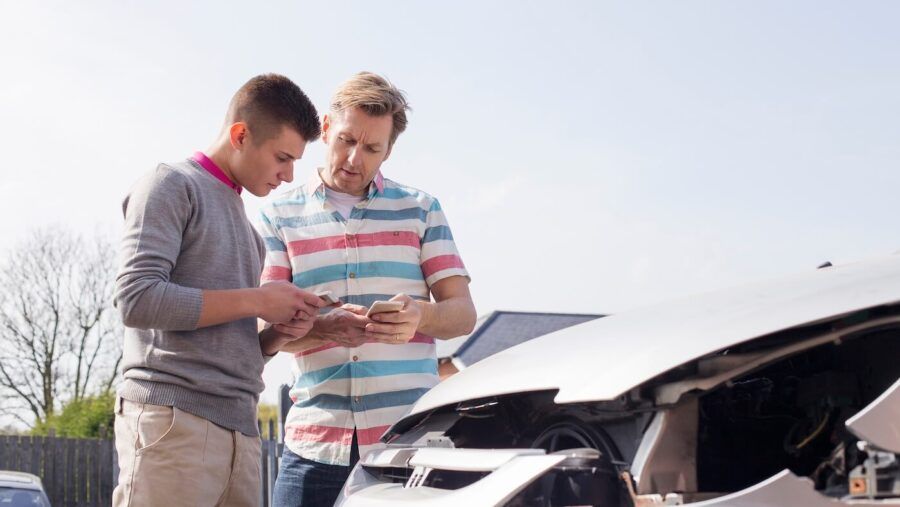Two male drivers exchanging contact information after a minor car accident