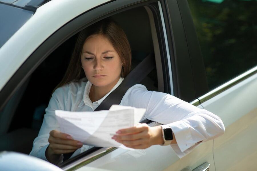 Concerned young woman sitting in the white car and reviewing her mail