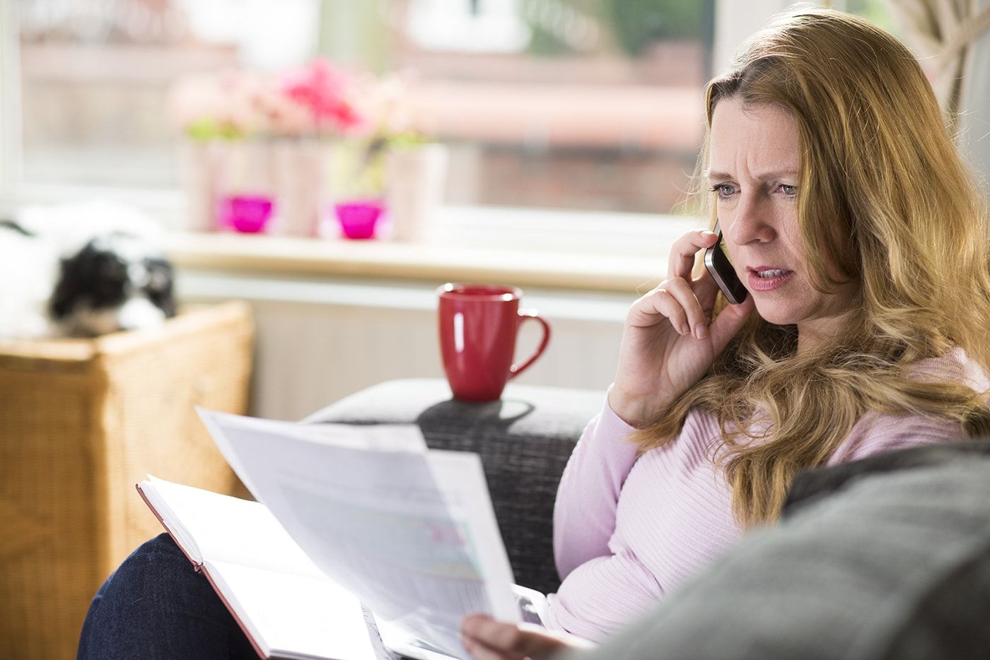 woman on the phone looking slightly concerned while holding papers