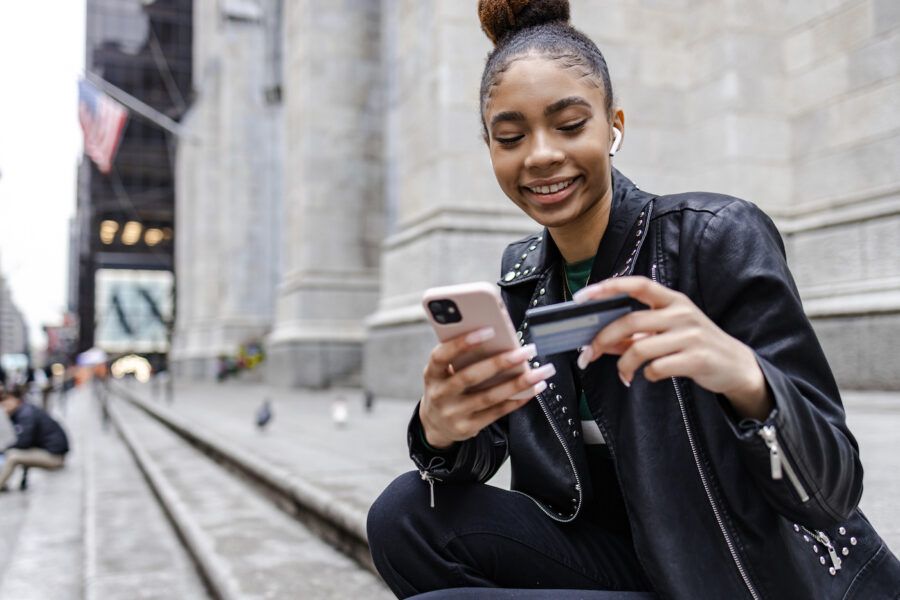 Young woman using credit card and mobile phone to shop online, using purchase protection