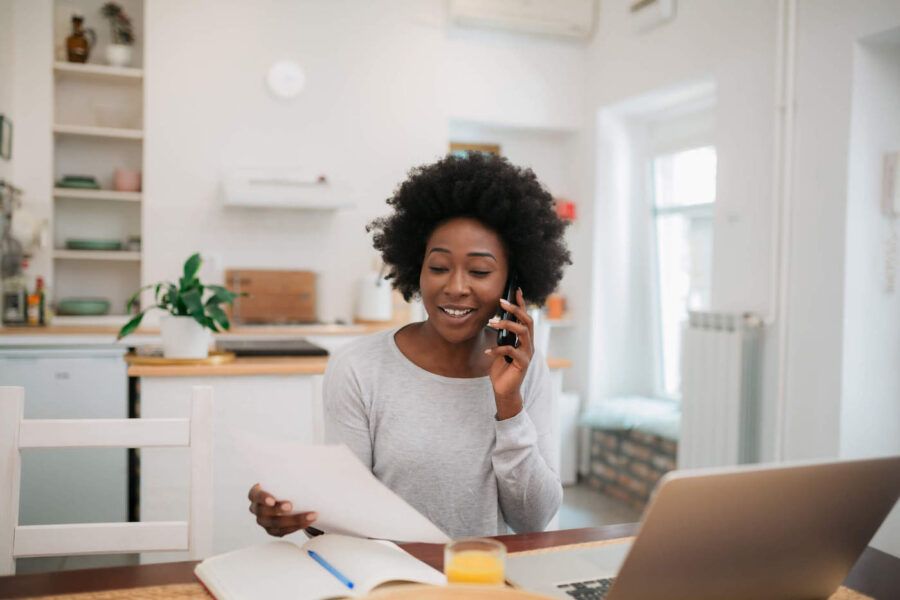 Young African American woman on the phone holding a piece of paper.